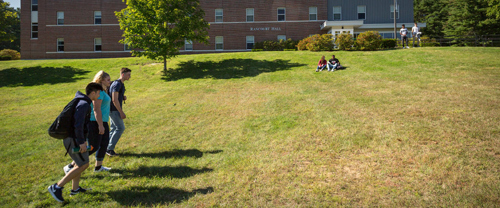 Students hanging out on lawn in front of Rancourt Hall residence hall