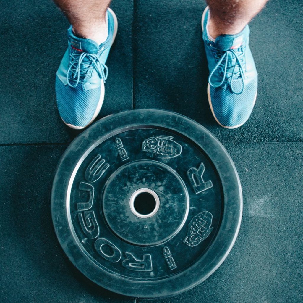 Birds-eye view photo of shoes next to a weight. Photo by Victor Freitas.