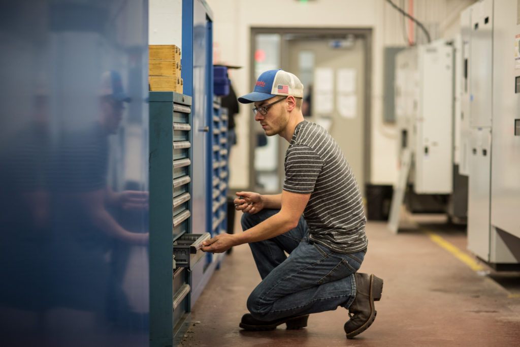 A male student gathers materials needed to complete a project in the Precision Machining Technology lab at Central Maine Community College.