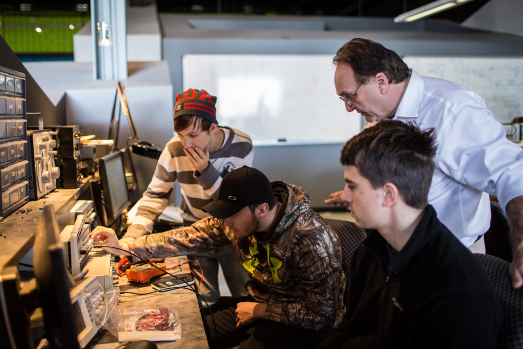 Three students and an instructor work intently in the Electromechanical Technology Lab at Central Maine Community College.