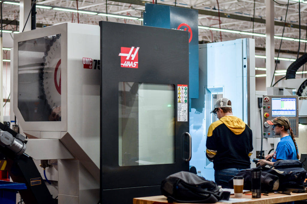 A male student works with a state-of-the-art 5-axis computer numerical control (CNC) machine in the new Precision Machining Technology lab at Central Maine Community College.