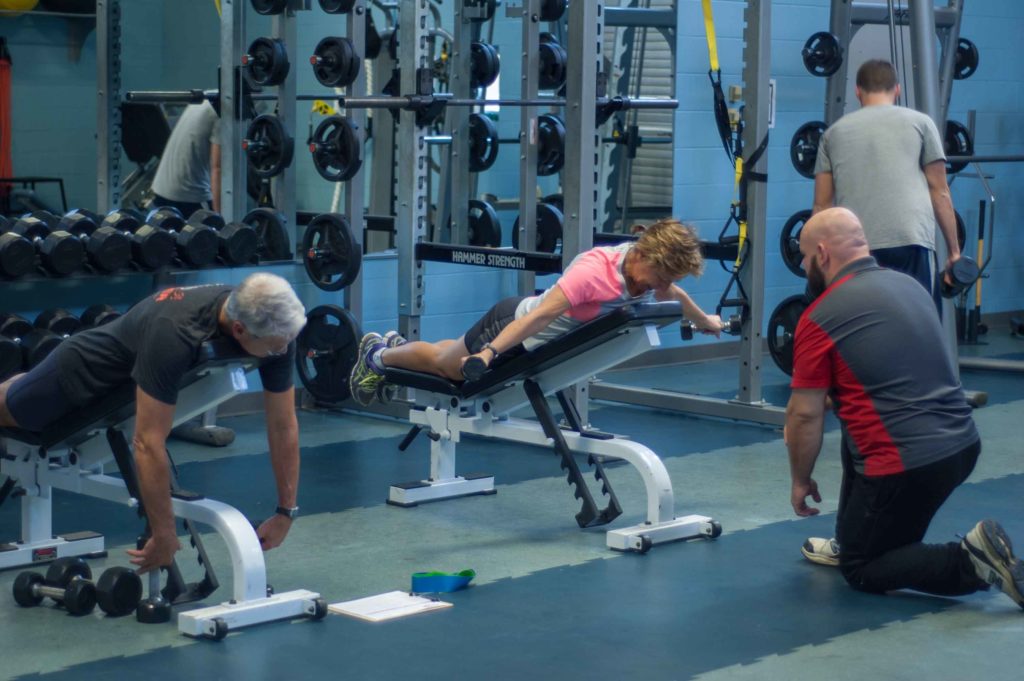 A male and female utilize a professional personal trainer in the Mustang Fitness Center at Central Maine Community College.