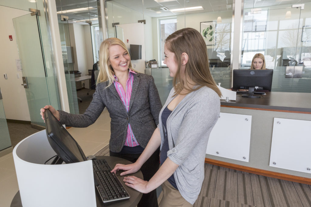 A female admissions representative discusses enrollment options with a female student in the admissions office