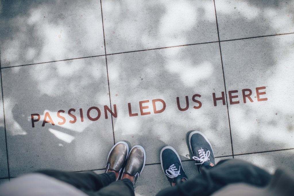 Birds-eye view of two individuals shoes looking down at a sidewalk that reads 