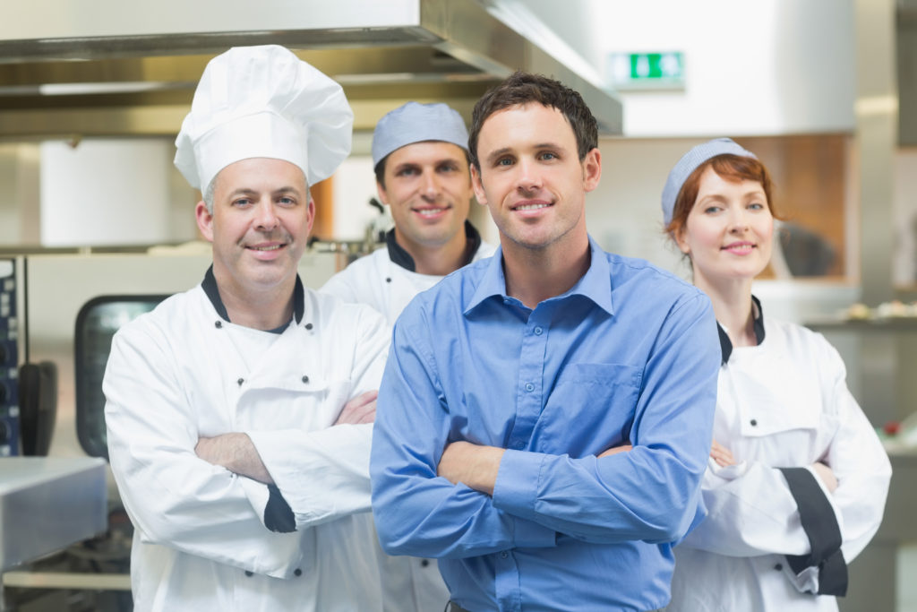 Restaurant manager with culinary staff in a professional kitchen.