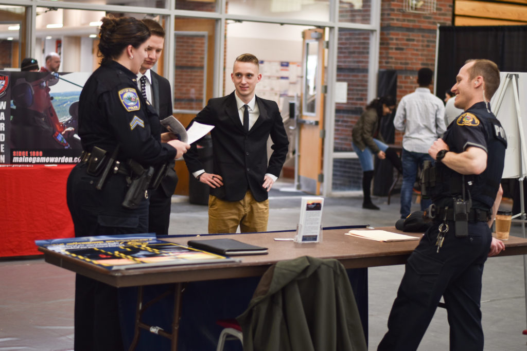 Three police officers and a criminal justice student attend the Criminal Justice Club Job Fair