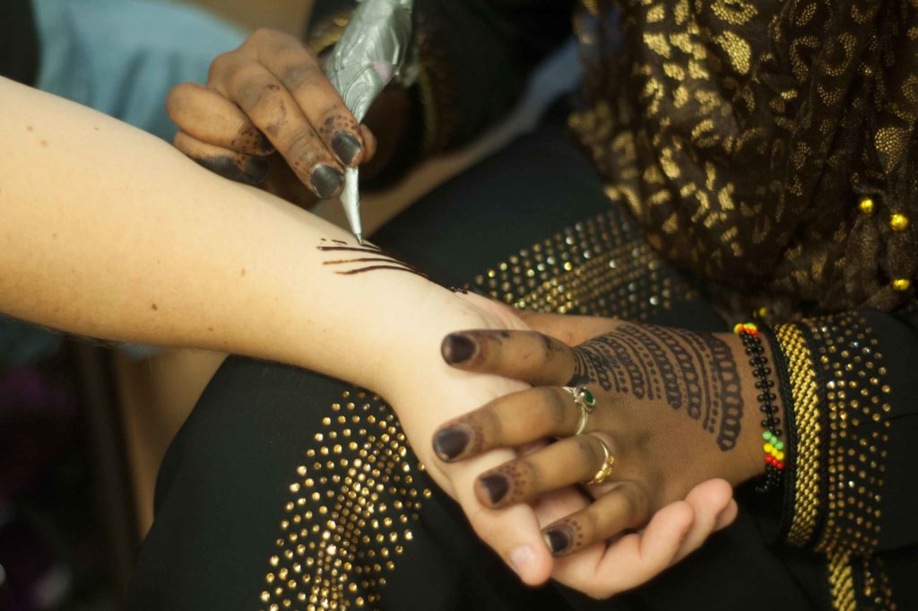 A student from the Muslim Student Association does henna on another student's arm