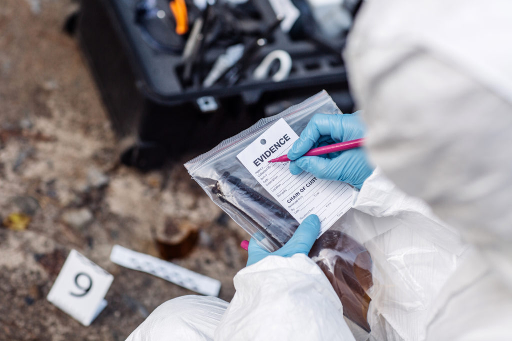 Close up of blue-gloved hand, writing an evidence ticket at a crime scene