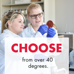 Two white women with blond hair in white lab coats in a science lab holding a bacteria sample up to review it. Text overlay reads "Choose from over 40 degrees"