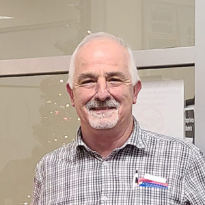 Headshot of ray masse in a white, red and blue plaid shirt.