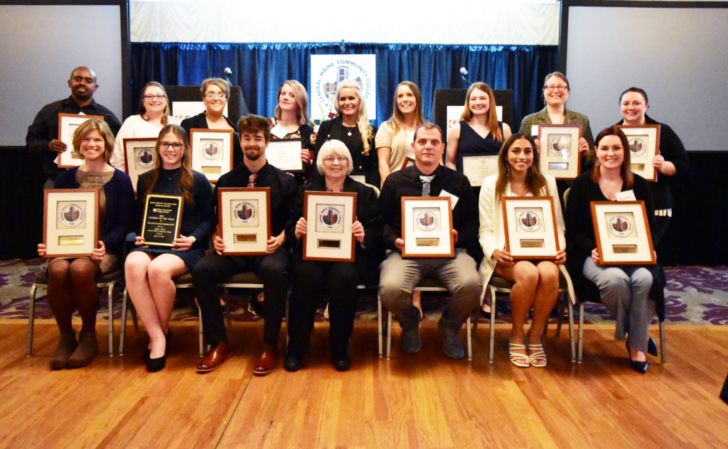 A group of students, faculty and staff posing together with their awards.