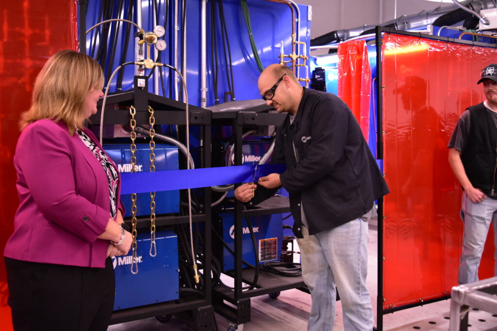 Darrick Bryant, a student in CMCC's first welding academy cohort, cuts the ceremonial ribbon to celebrate the opening of the new Welding Lab. 